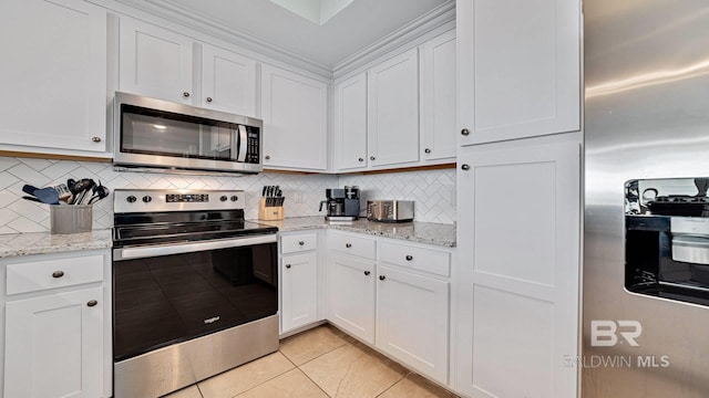 26688 Perdido Beach Blvd Unit 1203, Orange Beach, AL 36561 - kitchen with stainless steel appliances, light tile patterned flooring, white cabinetry, decorative backsplash, and light stone counters
