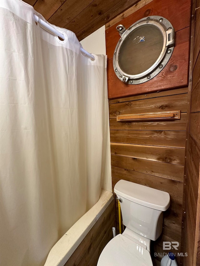 bathroom featuring wooden walls, shower / bath combination with curtain, wood ceiling, and toilet