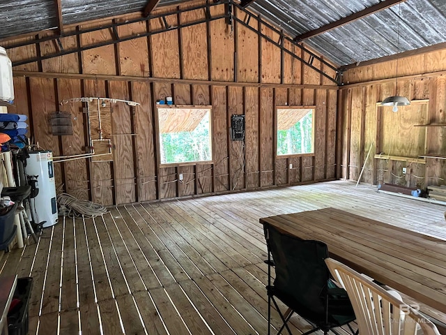 interior space with hardwood / wood-style flooring, vaulted ceiling, wood walls, and water heater