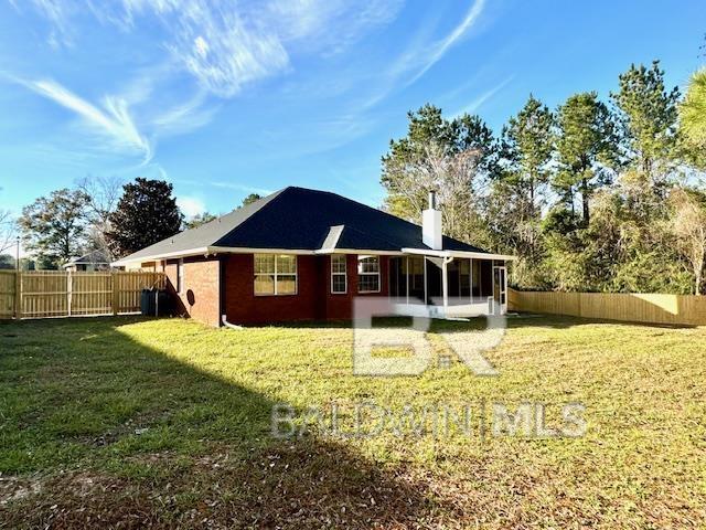 rear view of house featuring a sunroom and a yard