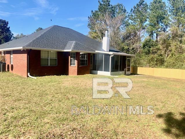 back of property featuring a yard and a sunroom