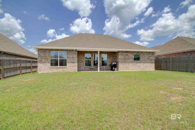 rear view of house with a lawn, brick siding, and a fenced backyard