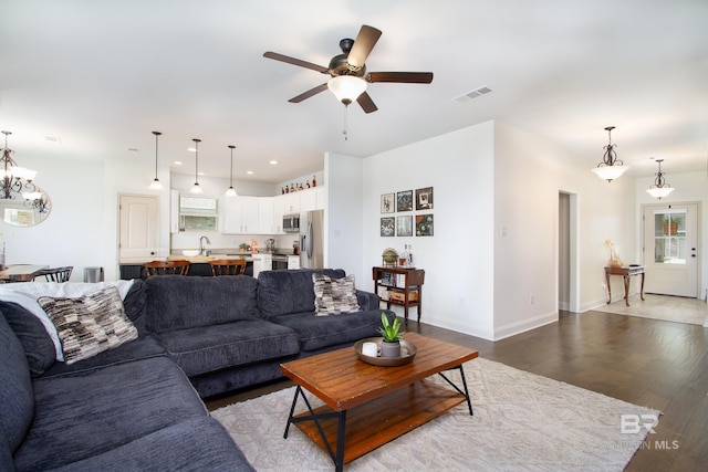 living room featuring dark wood-style flooring, ceiling fan with notable chandelier, recessed lighting, baseboards, and visible vents