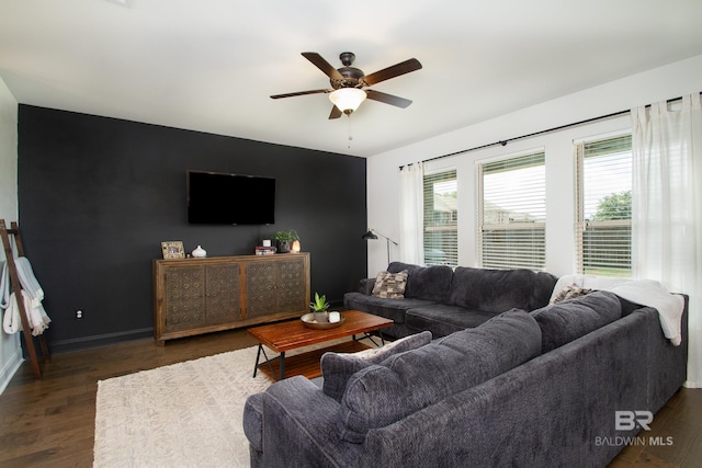 living room with baseboards, a ceiling fan, and dark wood-style floors
