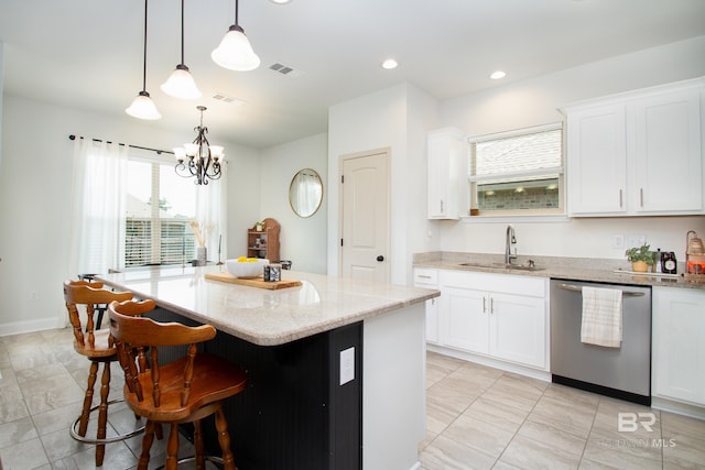 kitchen with visible vents, a center island, light stone countertops, dishwasher, and a sink