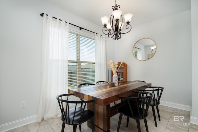 dining space with baseboards and a notable chandelier
