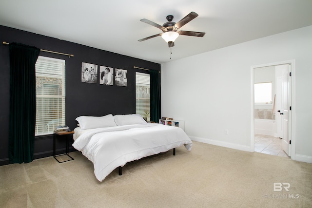 bedroom featuring connected bathroom, a ceiling fan, baseboards, and light colored carpet