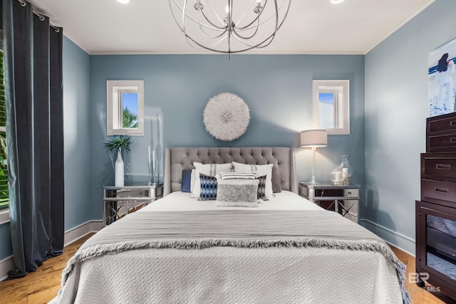 bedroom with baseboards, ornamental molding, wood finished floors, and a chandelier