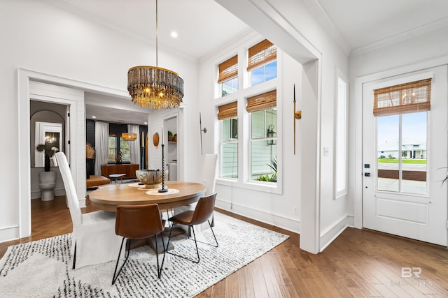 dining area featuring crown molding, baseboards, wood finished floors, and a notable chandelier