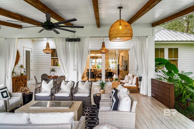 living room featuring beamed ceiling, light hardwood / wood-style flooring, ceiling fan, and a wealth of natural light