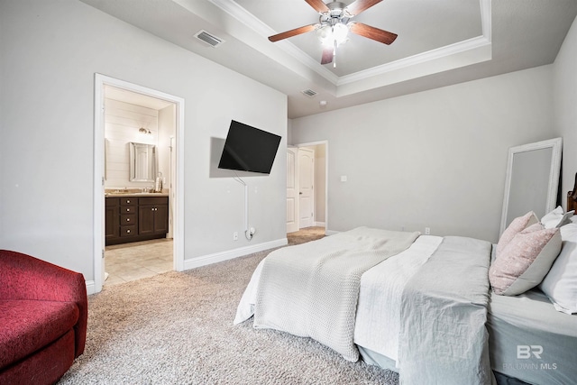 carpeted bedroom with ensuite bathroom, crown molding, ceiling fan, and a raised ceiling