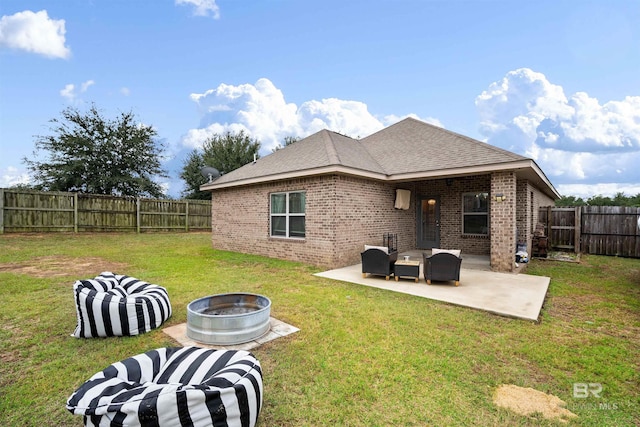 back of property with a lawn, a patio, and an outdoor living space with a fire pit