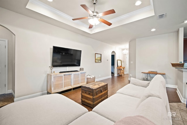 living room featuring hardwood / wood-style floors, ceiling fan, crown molding, and a tray ceiling