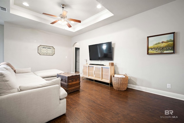 living room with ornamental molding, dark hardwood / wood-style flooring, ceiling fan, and a tray ceiling