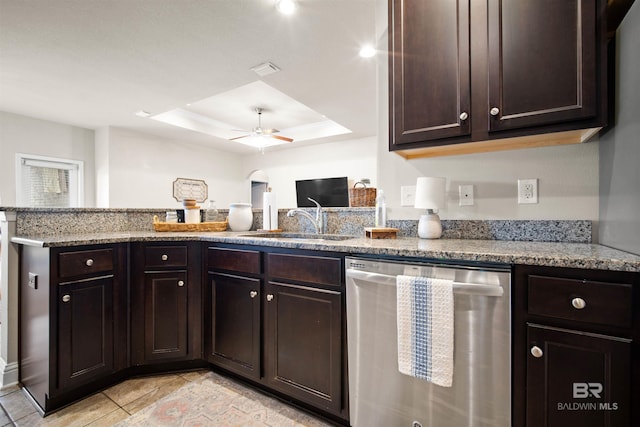 kitchen with dark brown cabinetry, stainless steel dishwasher, and a tray ceiling