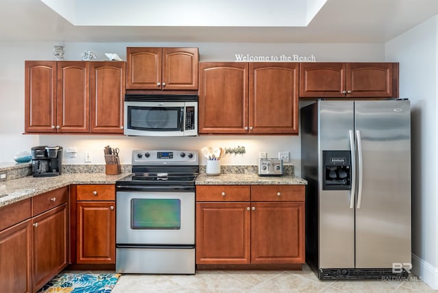 kitchen featuring appliances with stainless steel finishes, light tile patterned floors, and light stone counters