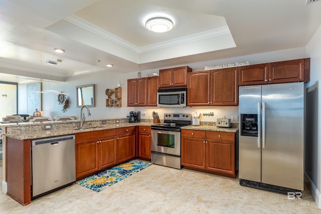 kitchen featuring stainless steel appliances, a raised ceiling, light stone countertops, sink, and kitchen peninsula