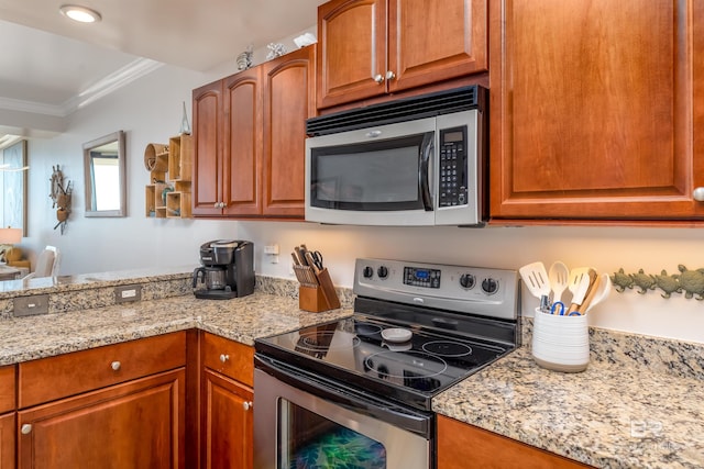 kitchen with light stone countertops, appliances with stainless steel finishes, and ornamental molding