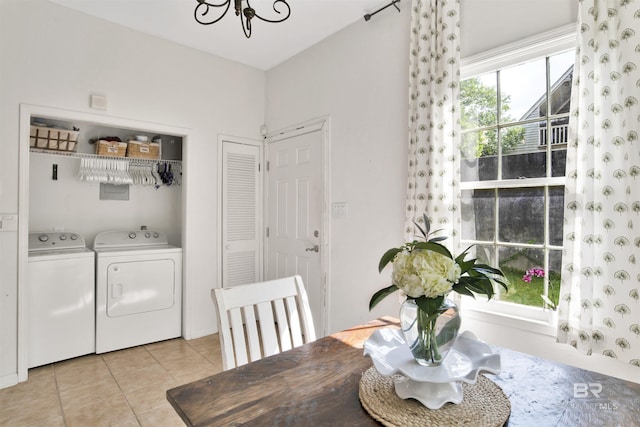 tiled dining space featuring washing machine and dryer and an inviting chandelier