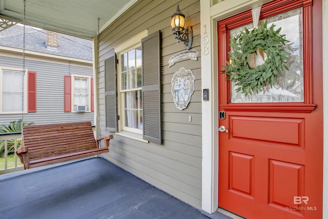 doorway to property with cooling unit and a porch