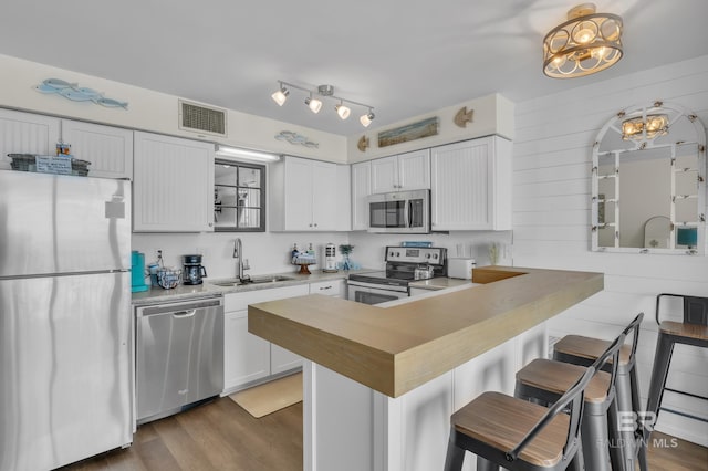 24522 Perdido Beach Blvd Unit 3705, Orange Beach, AL 36561 - kitchen featuring a peninsula, visible vents, stainless steel appliances, a sink, and wood finished floors