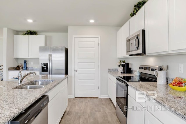 kitchen with light stone counters, sink, white cabinets, and appliances with stainless steel finishes