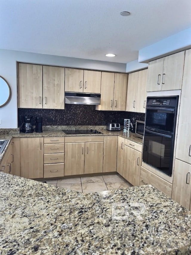 521 W Beach Blvd Unit 1703, Gulf Shores, AL 36542 - kitchen with light brown cabinets, decorative backsplash, stone counters, under cabinet range hood, and black appliances