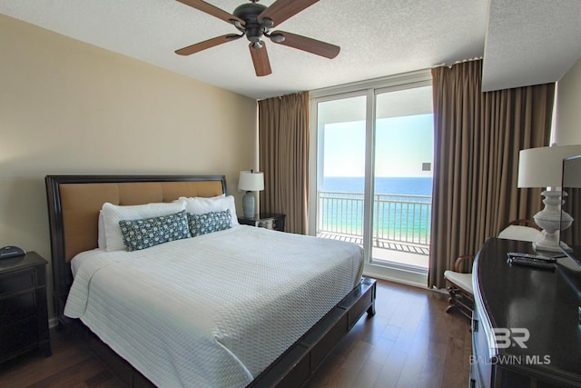 bedroom featuring ceiling fan, a textured ceiling, dark wood-type flooring, and access to exterior