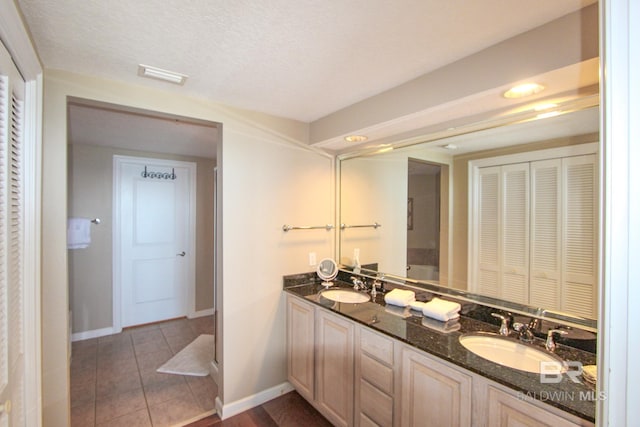 bathroom with a textured ceiling, tile patterned flooring, and vanity