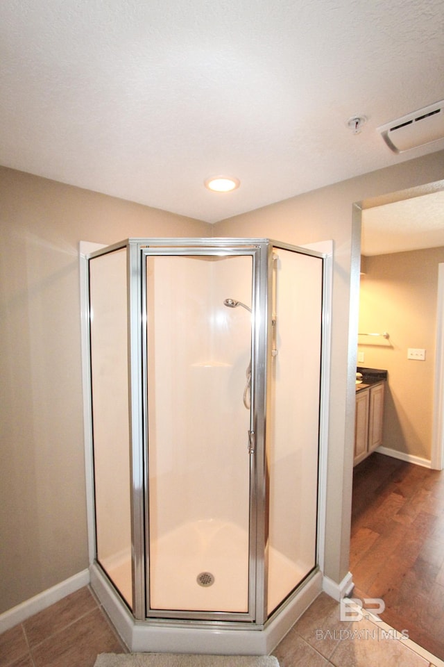 bathroom with hardwood / wood-style flooring, vanity, and an enclosed shower