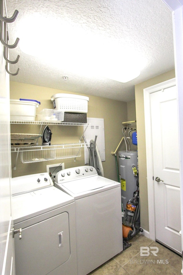 laundry area with washing machine and clothes dryer, water heater, a textured ceiling, and tile patterned floors