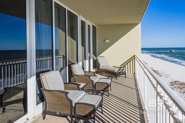 balcony with a water view and a view of the beach