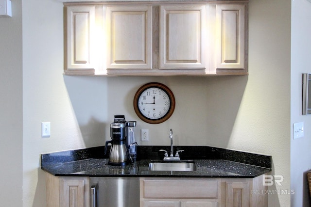 kitchen featuring dark stone countertops, sink, and light brown cabinets