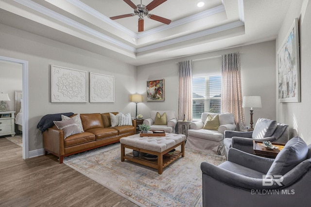 living room with crown molding, a tray ceiling, and hardwood / wood-style floors