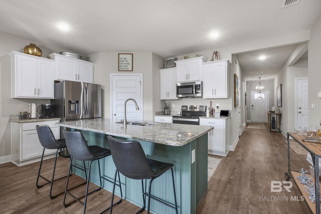 kitchen with stainless steel appliances, sink, an island with sink, and white cabinets