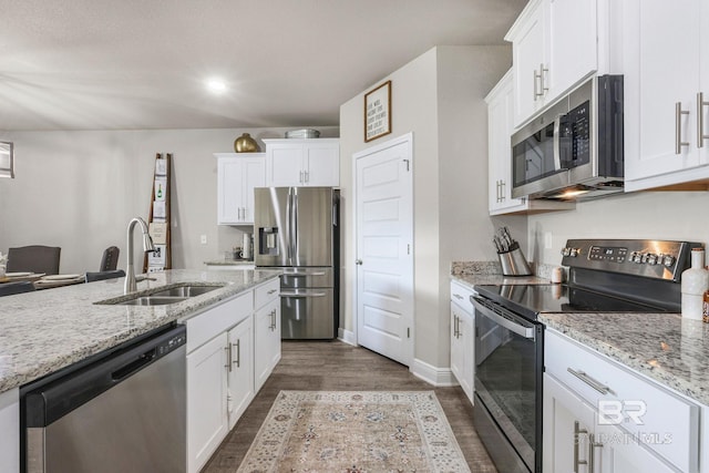 kitchen with light stone counters, appliances with stainless steel finishes, sink, and white cabinets