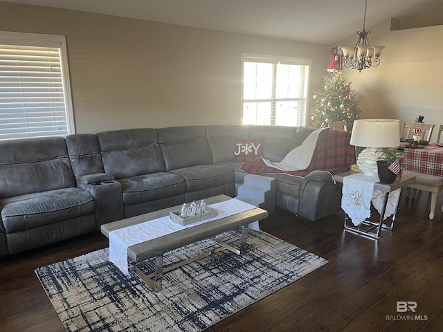 living room with lofted ceiling, dark hardwood / wood-style floors, and an inviting chandelier