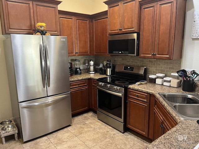 kitchen featuring decorative backsplash, sink, stainless steel appliances, and light stone counters