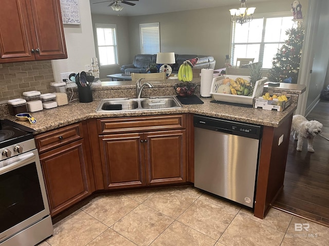 kitchen featuring sink, stainless steel appliances, backsplash, light tile patterned floors, and ceiling fan with notable chandelier