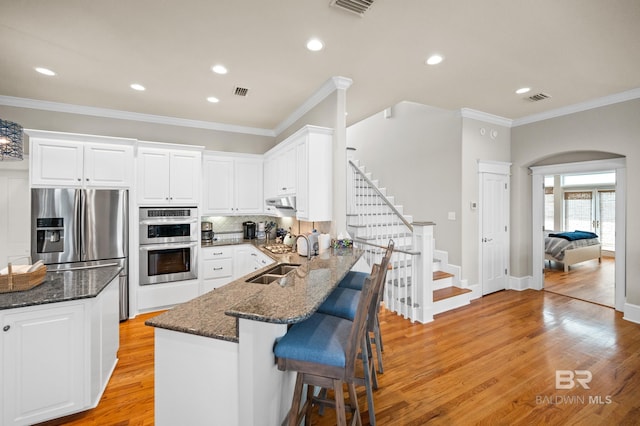 kitchen with light hardwood / wood-style flooring, kitchen peninsula, a kitchen breakfast bar, white cabinets, and sink