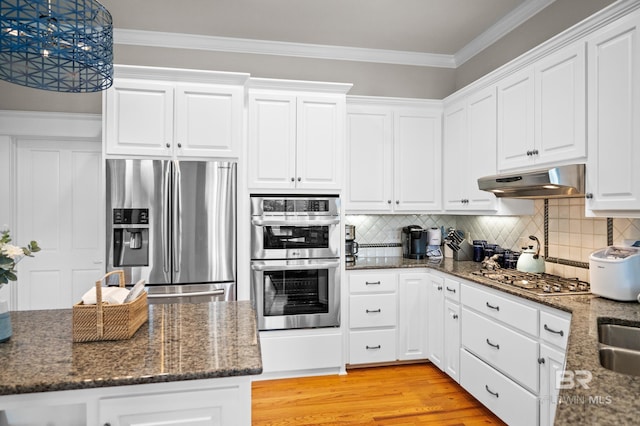 kitchen featuring stainless steel appliances, dark stone countertops, backsplash, and white cabinets