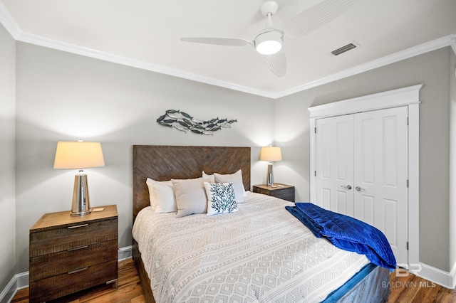 bedroom with dark wood-type flooring, ceiling fan, a closet, and crown molding