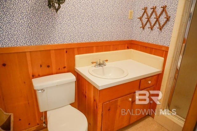 full bath featuring vanity, a wainscoted wall, a stall shower, and toilet