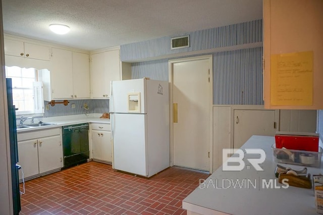 kitchen featuring a sink, visible vents, black dishwasher, brick patterned floor, and freestanding refrigerator