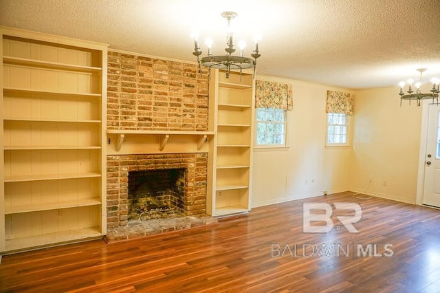 unfurnished living room featuring baseboards, wood finished floors, a textured ceiling, and a notable chandelier