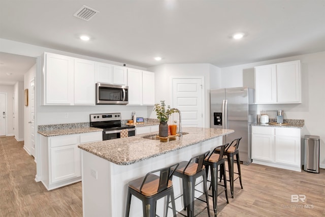 kitchen with sink, white cabinetry, stainless steel appliances, and a kitchen island with sink