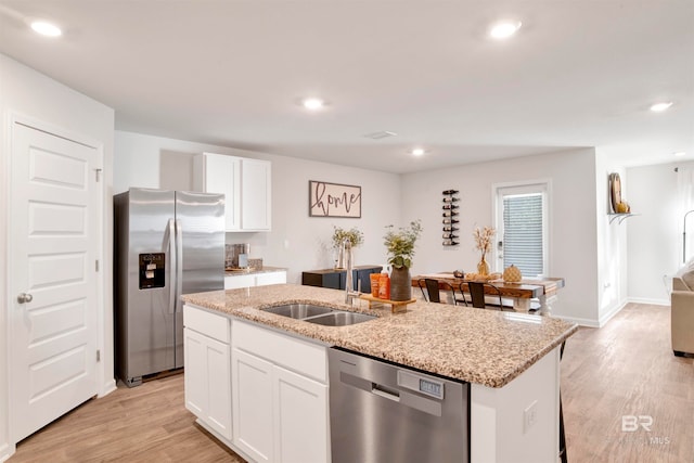 kitchen with white cabinetry, sink, stainless steel appliances, light hardwood / wood-style flooring, and a kitchen island with sink