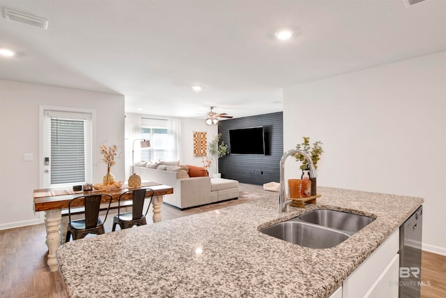 kitchen featuring light stone countertops, light hardwood / wood-style flooring, ceiling fan, and sink