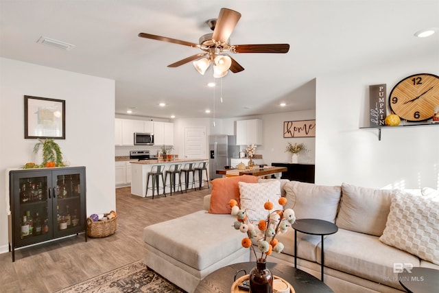 living room featuring light wood-type flooring and ceiling fan