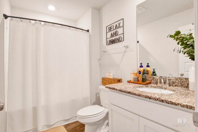 bathroom with hardwood / wood-style floors, vanity, toilet, and walk in shower